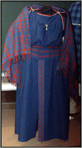 A replica of a Viking-era woman's dress and slip on display at the Danish National Museum in Copenhagen. These recreated articles were based in part on cloth fragments found in a Danish grave. The original outfit was blue wool, dyed with indigo. It was held up with shoulder straps secured with bowl-shaped brooches. The slip was fabricated from bleached linen.